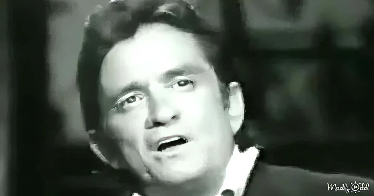 A man with curly hair and a suit, possibly from a film or television show, is shown in a close-up shot.