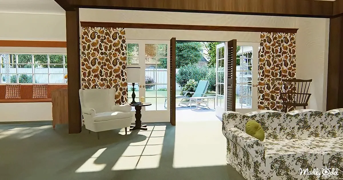 A sunlit living room with floral-patterned furniture, paisley wallpaper, and a view of a backyard with a lounge chair.