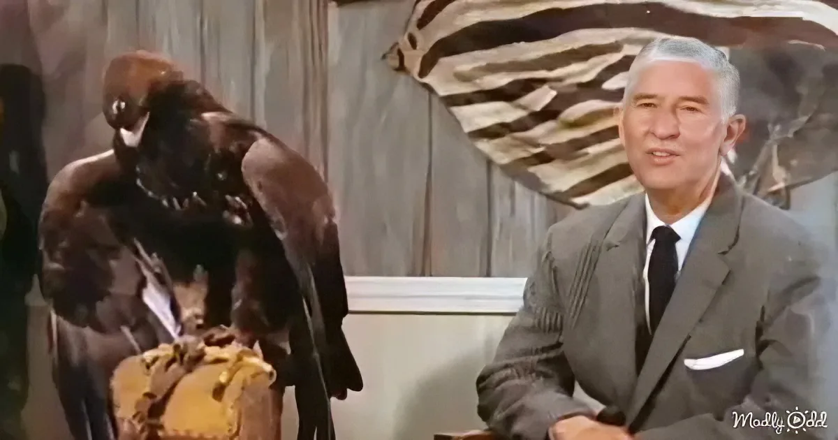 A man in a suit sits at a desk, while a large bird perches on a person's shoulder in a dramatic scene.