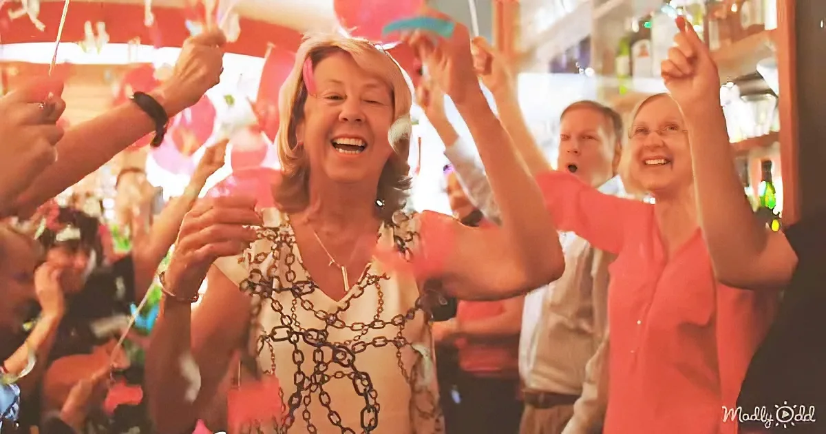 A woman in a chain dress celebrates joyfully with others at a lively party.