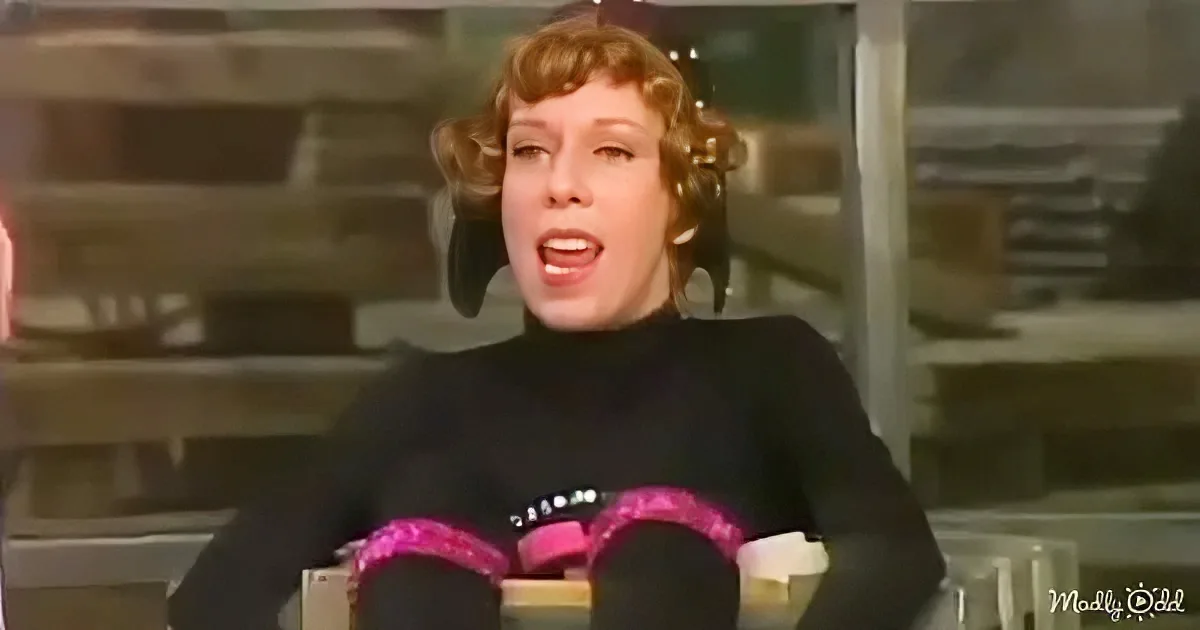A woman with curly hair, wearing a black turtleneck, is holding a book with pink pages.