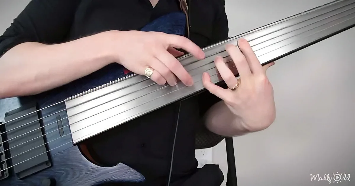 A person plays a bass guitar, focusing on the neck and hands.