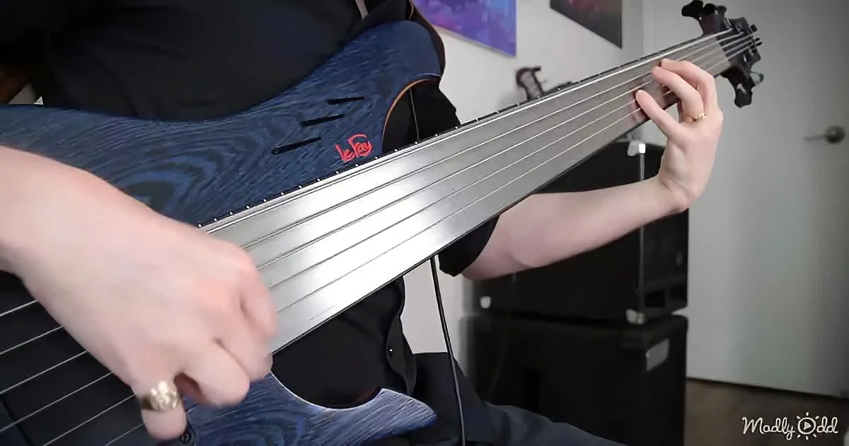 A person plays a unique multi-string electric guitar with a metallic body and intricate design.