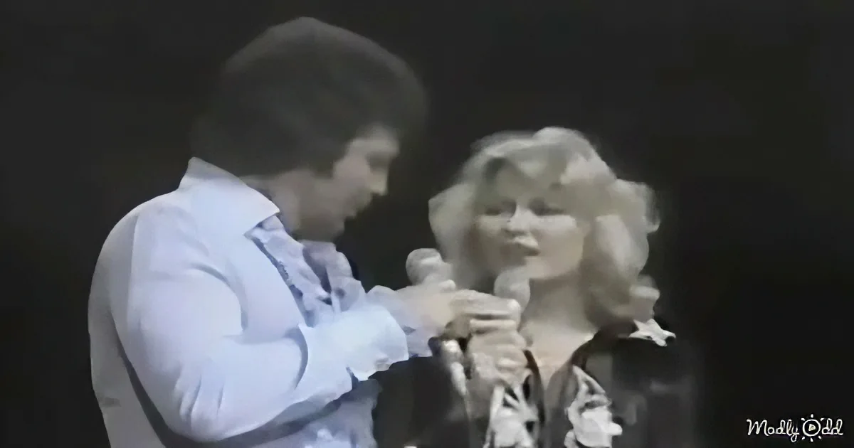 A man and woman are singing together, the man holding a microphone close to the woman's mouth.