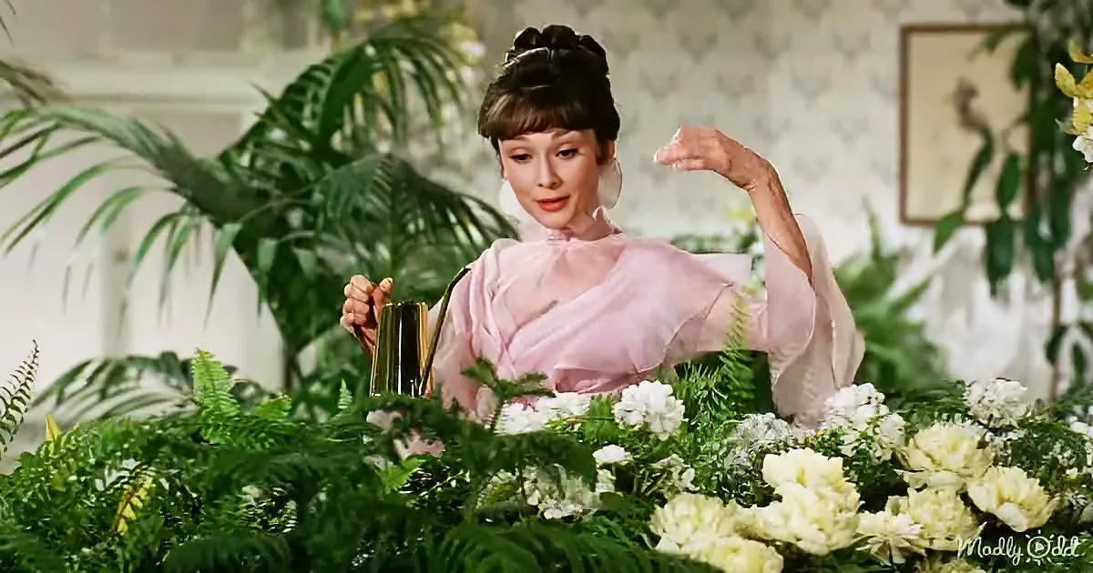 Audrey Hepburn in a pink dress, holding a teapot, surrounded by greenery and flowers.