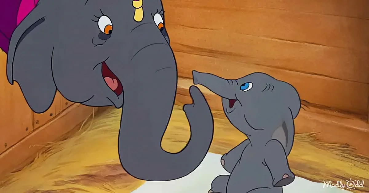 A baby elephant and its mother share a tender moment in a wooden enclosure.