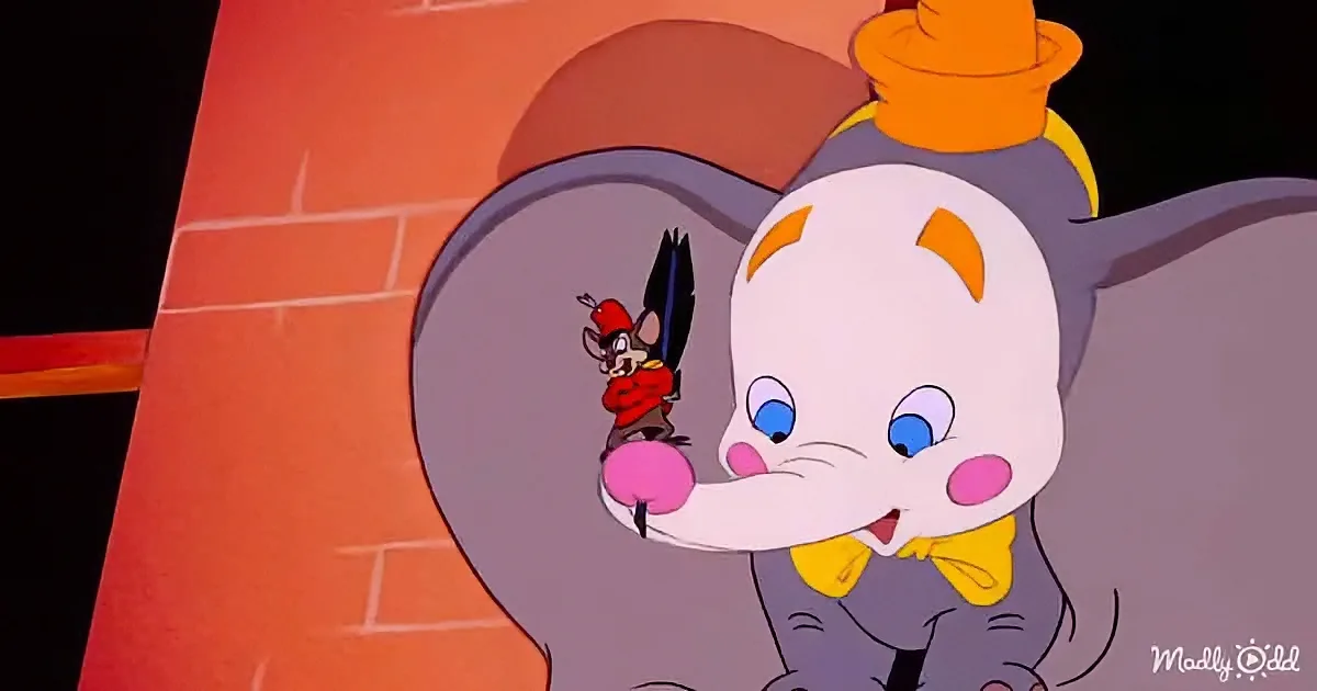 A cartoon elephant in a top hat holds a mouse in a red outfit, both looking surprised.
