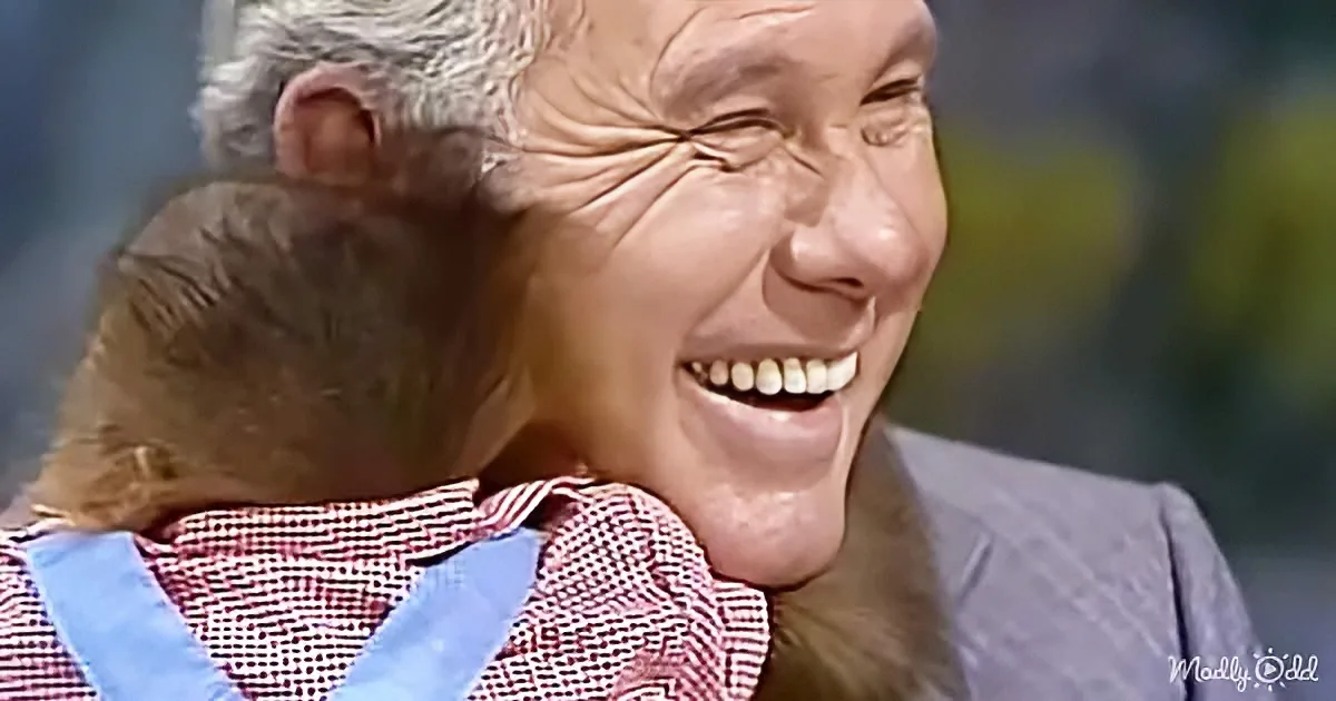 An elderly woman with white hair smiles widely, embracing a child in a red and white checkered shirt.