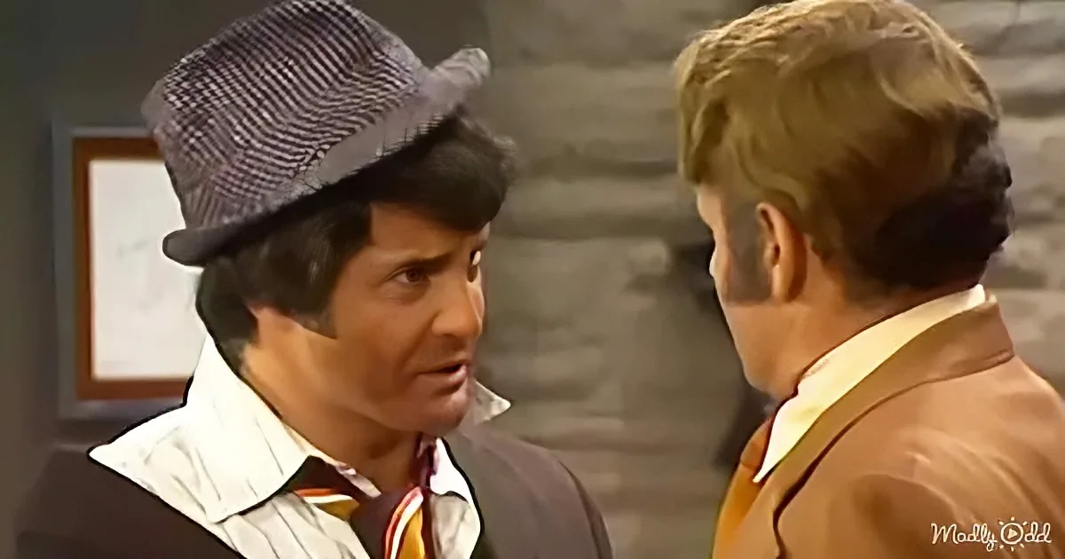 A man in a hat and suit is having a conversation with another man in a suit.