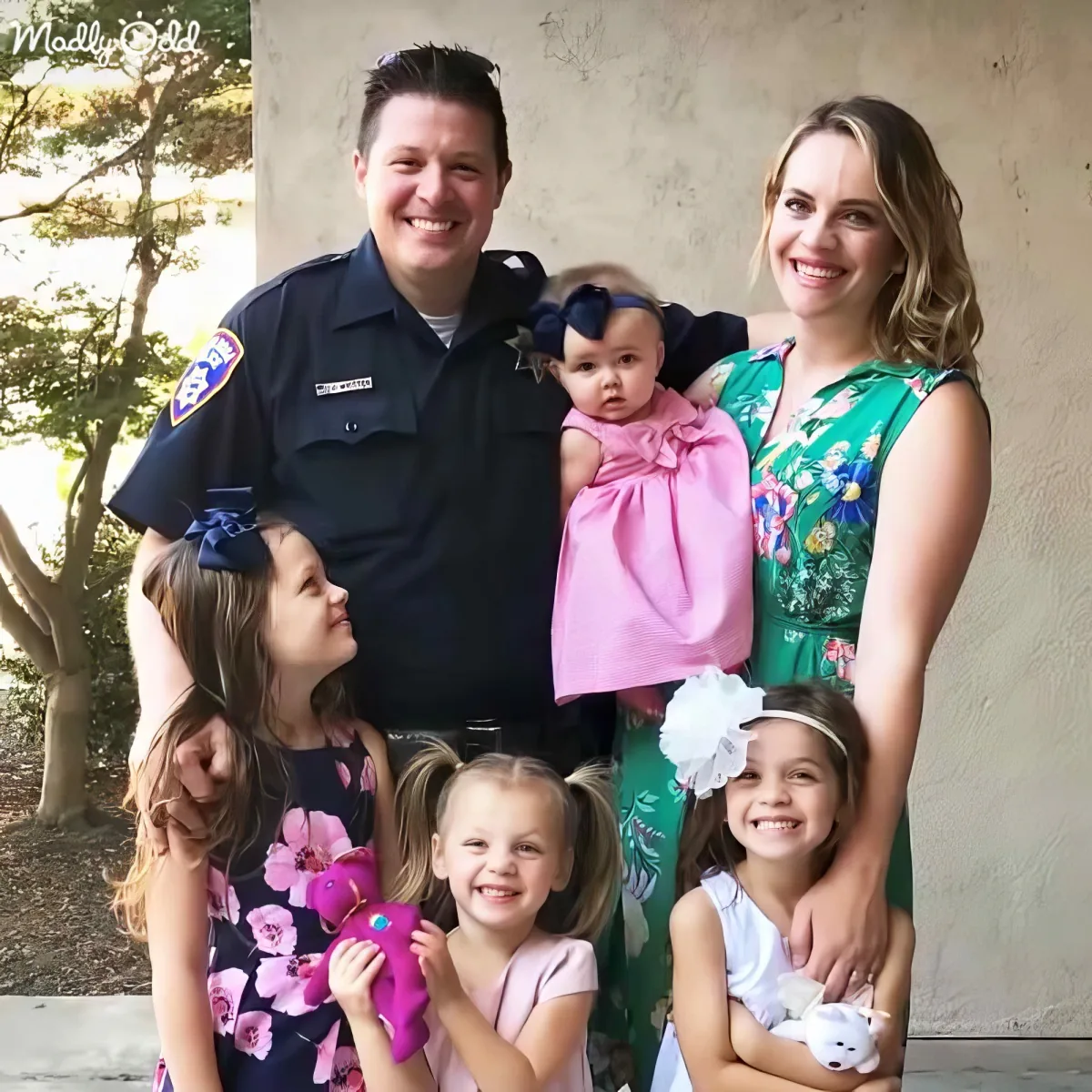 A police officer and his family, including four children, pose for a photo in front of a wall.
