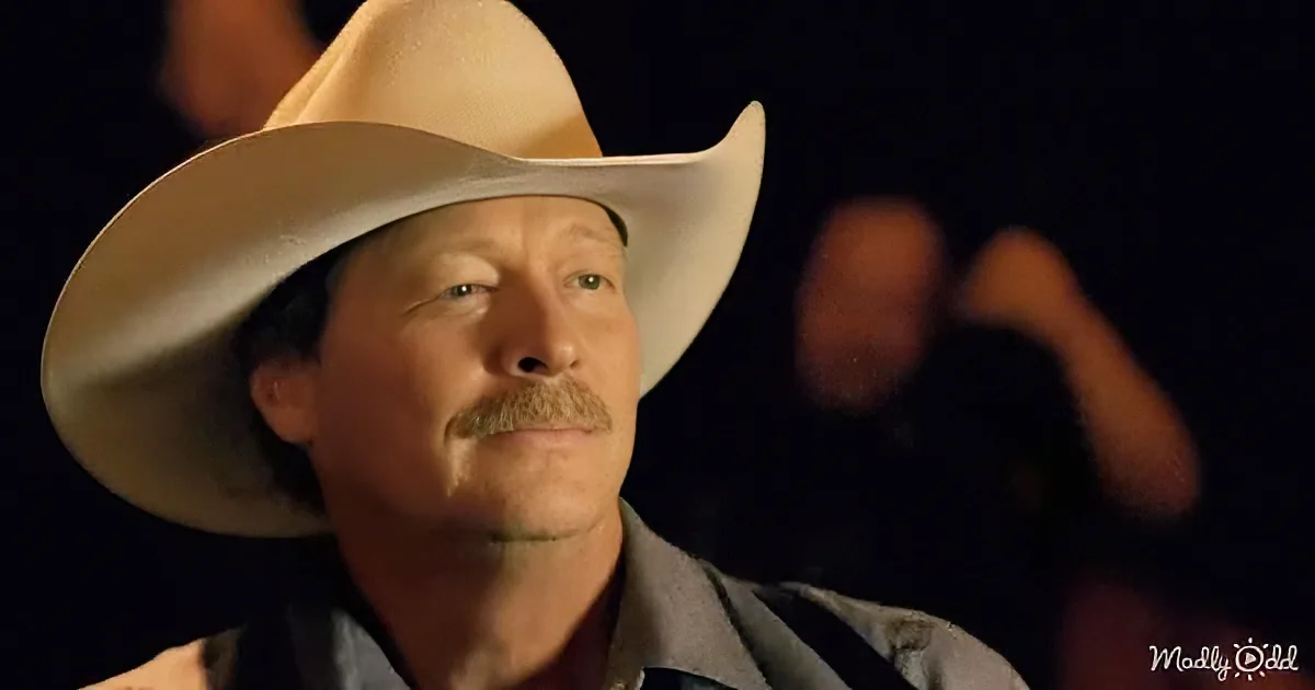 A man wearing a wide-brimmed cowboy hat and a collared shirt is the main subject, with a blurred figure in the background.