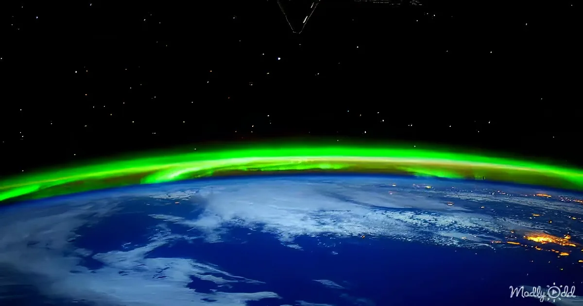 Aurora Borealis illuminates the Earth's horizon from space, with stars and Earth's curvature visible.