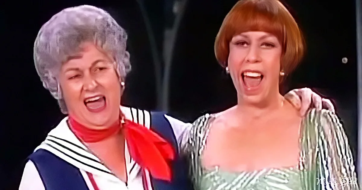 Two women in costumes, one in sailor outfit, both with expressive faces, seemingly singing or performing.