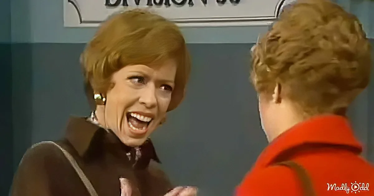 A woman in a brown outfit is laughing and gesturing with her hands while talking to another person in a red shirt.