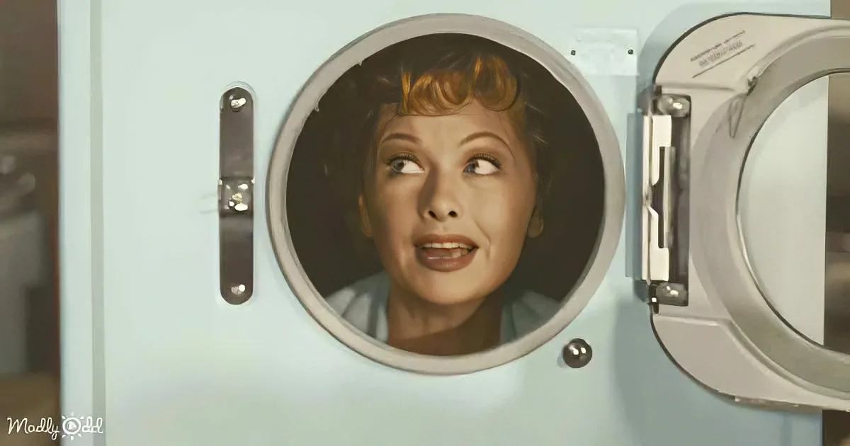 A woman with red hair looks surprised inside a light blue washing machine.