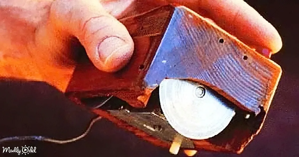 A hand holds a small, homemade device with a circular component and a wooden piece, possibly a homemade tool or gadget.
