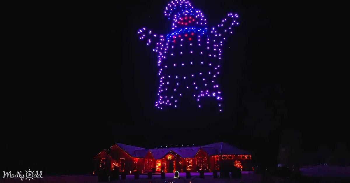 A drone display forms a dog shape above a building adorned with red lights.