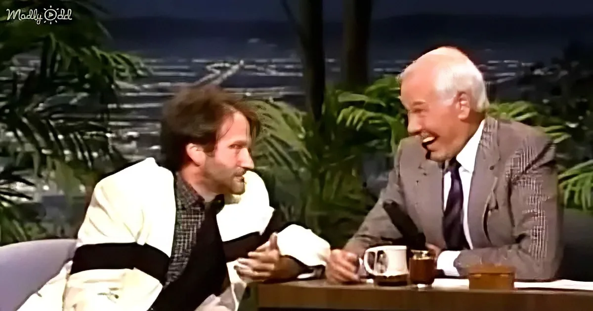 Two men in suits are seated at a table, laughing and enjoying a conversation.