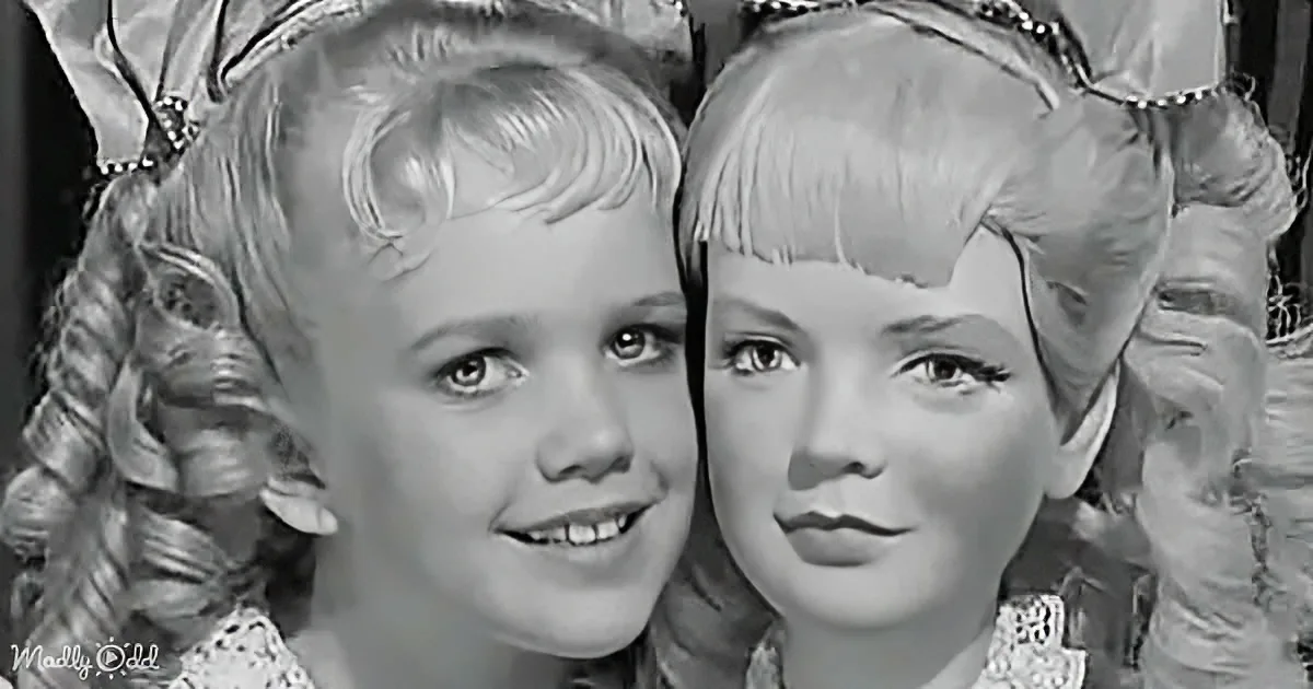 Two children in elaborate costumes with tiaras, smiling and looking directly at the camera.