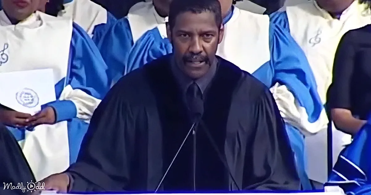 A man in a black graduation gown speaks at a podium, surrounded by choir members in blue and white robes.