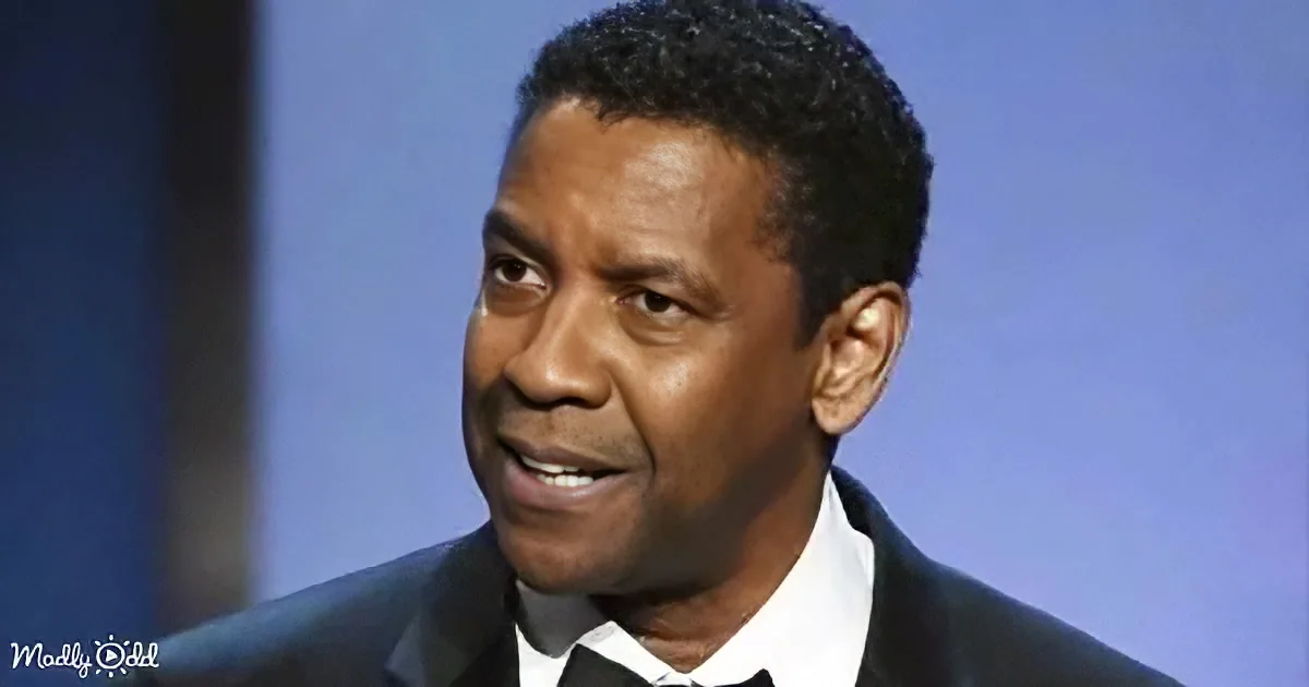 A man in a suit and tie, smiling, with short dark hair, against a blurred blue background.