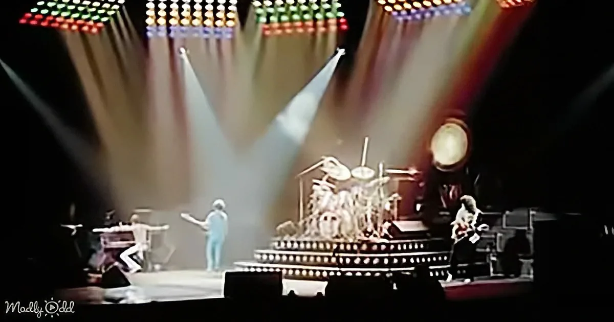 A band performs on a stage with colorful lights and a drum set prominently featured.