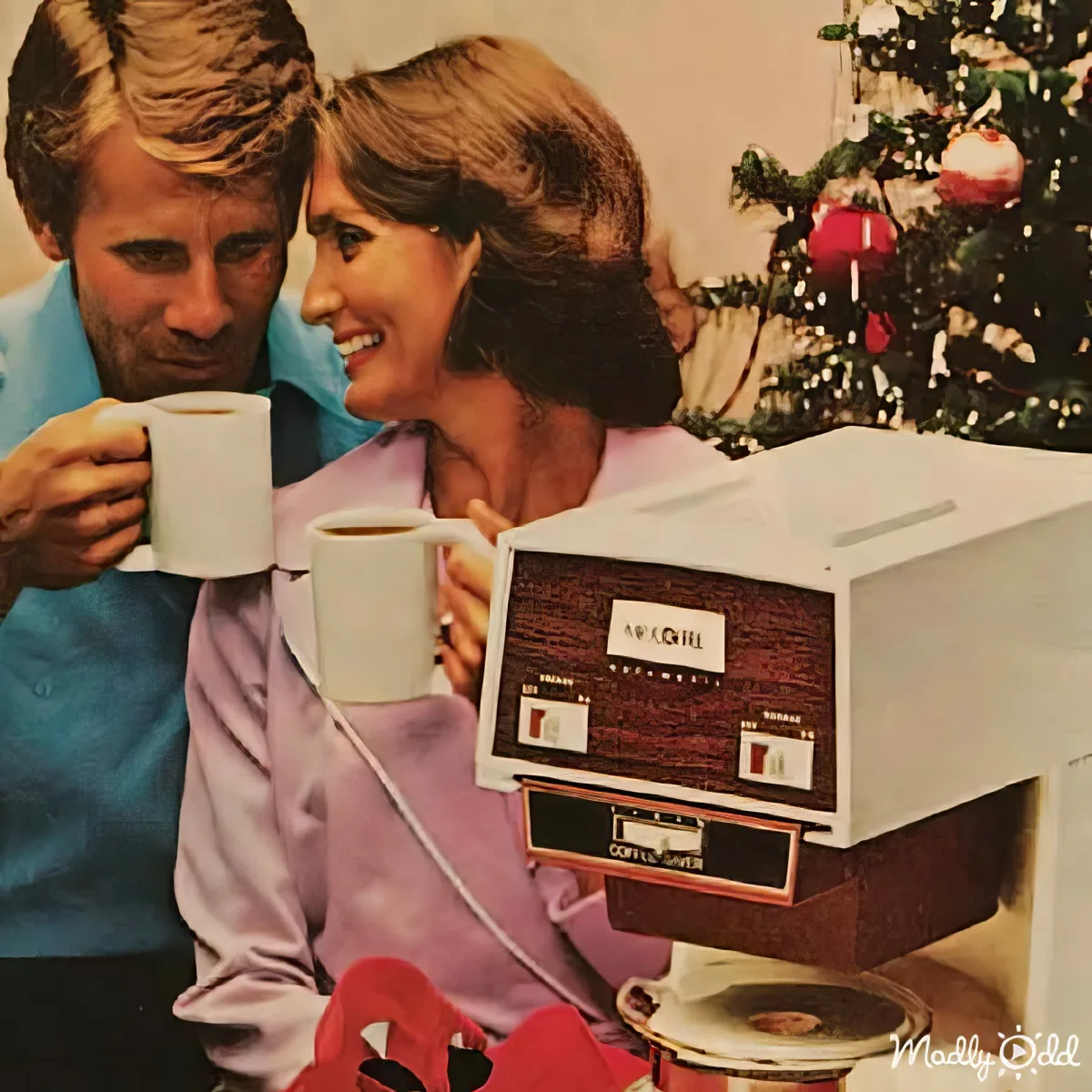 A couple in pajamas enjoys coffee near a vintage coffee maker with a Christmas tree in the background.