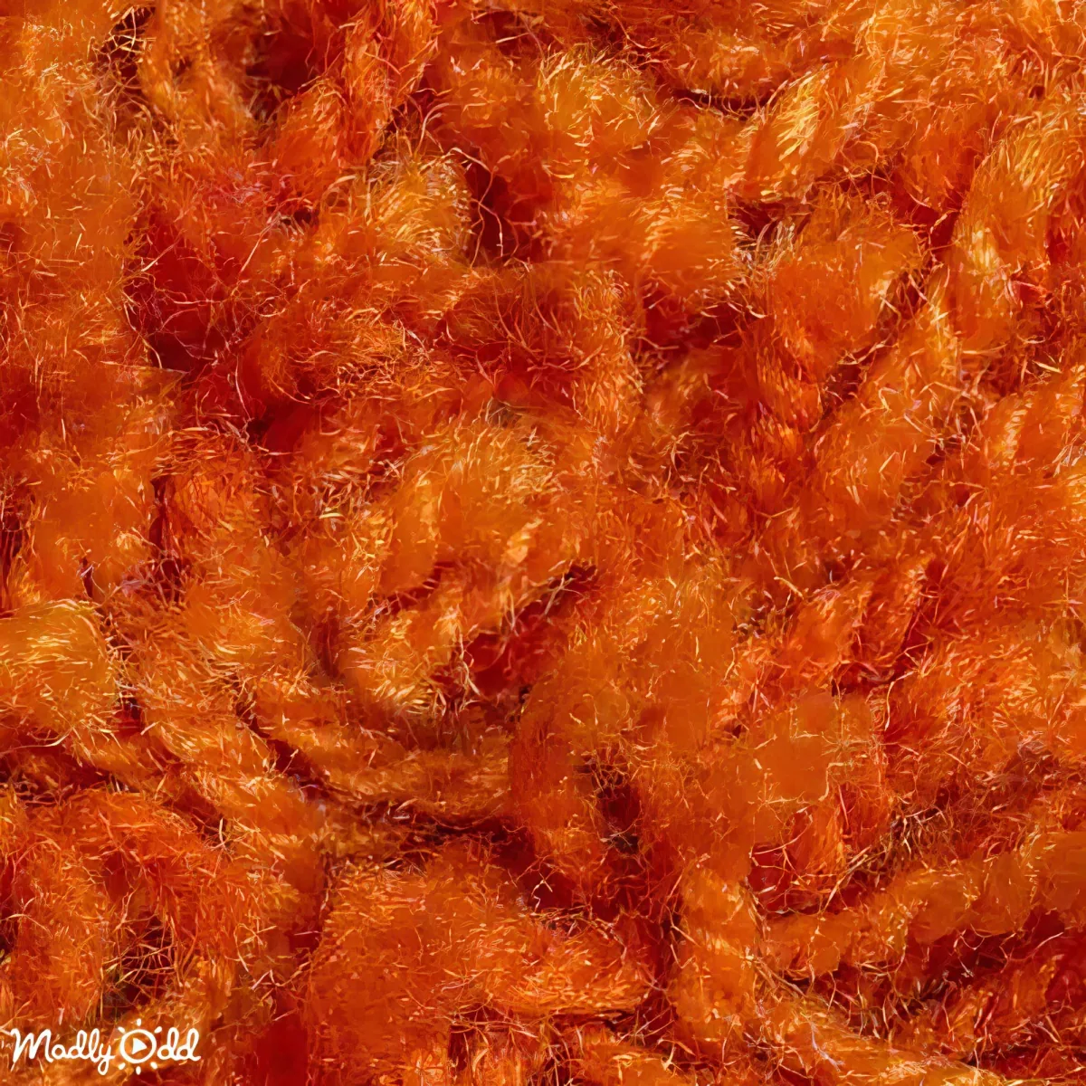 A close-up of a textured, orange fabric with a fuzzy, knitted appearance.