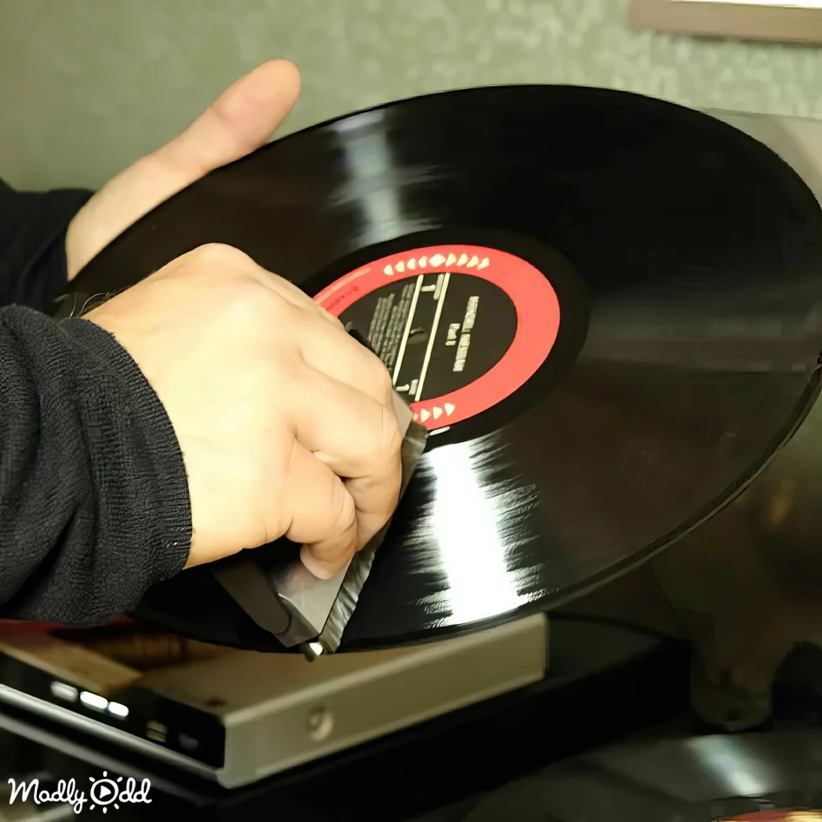 A person is cleaning a vinyl record with a brush on a turntable.