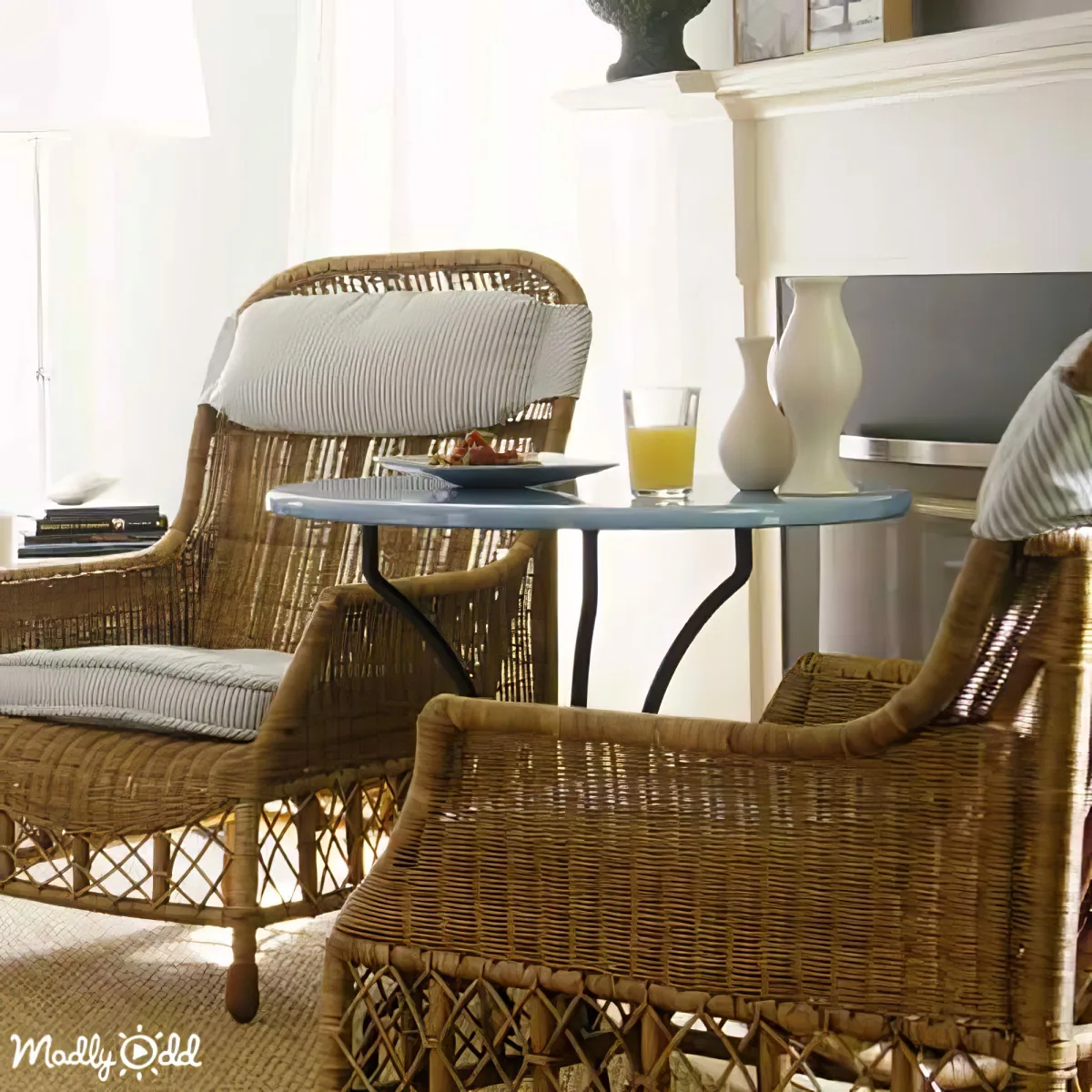 Rattan chairs with blue cushions and a small table with a glass of orange juice and a plate of food.