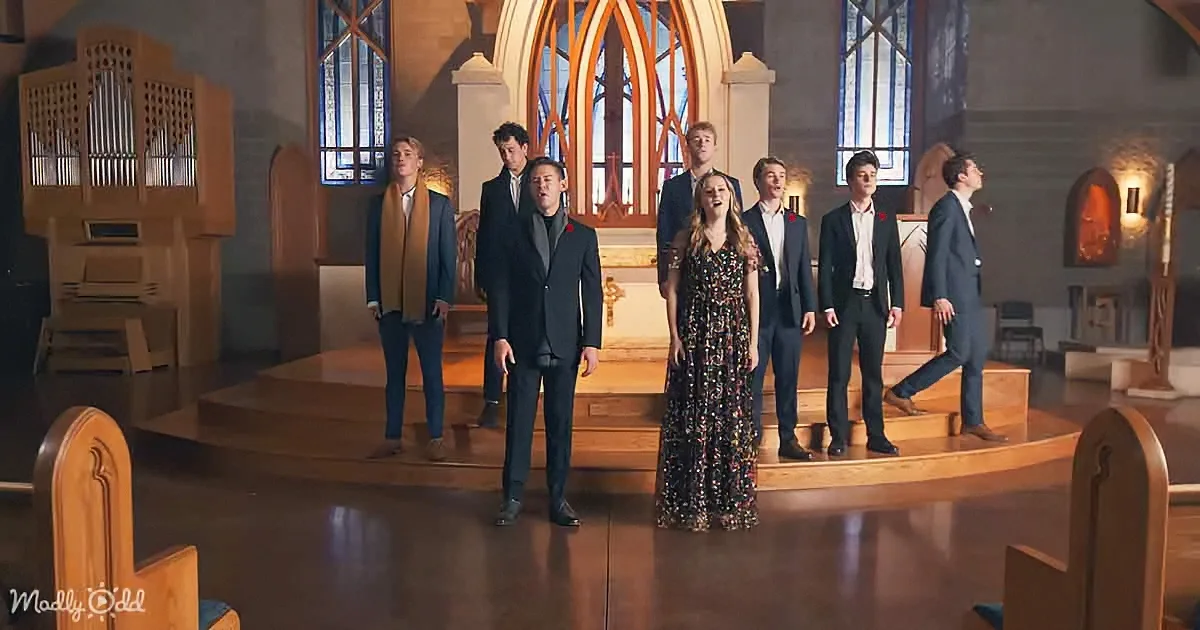 A group of people in formal attire stands on a church altar, singing.