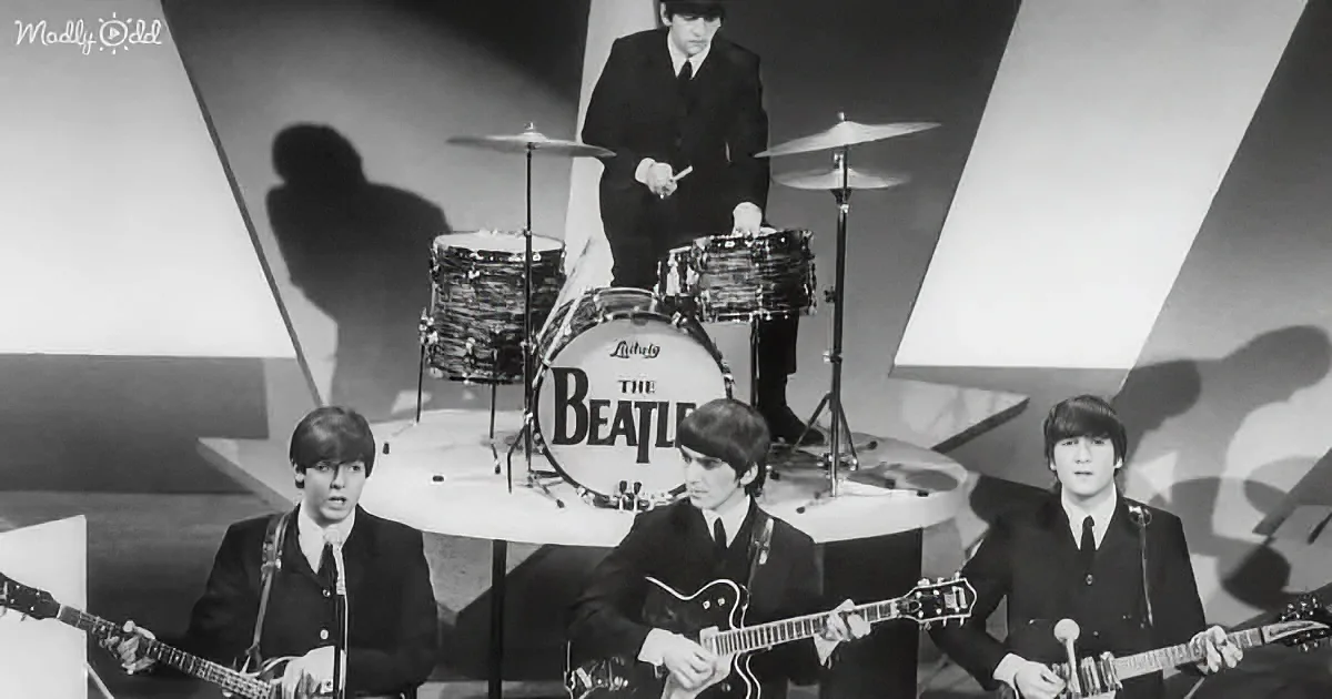 The Beatles perform on stage with guitars and drums, dressed in suits, under dramatic lighting.