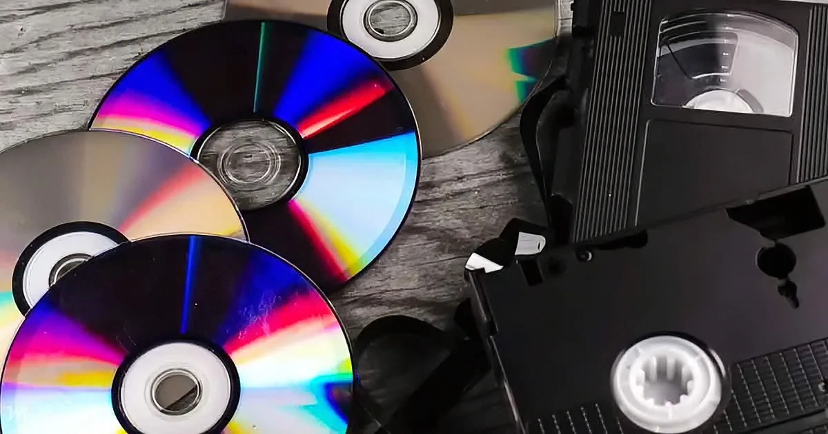 A pile of CDs and a VHS tape on a wooden surface.