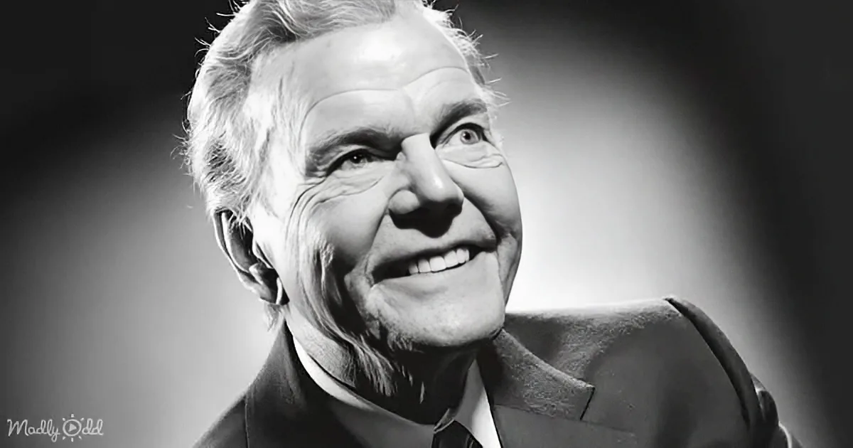 An older man in a suit smiles warmly, his face illuminated against a dark background.
