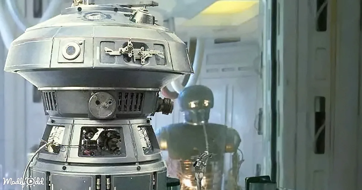 A metallic, dome-shaped robot with intricate details stands in a futuristic setting, with another robot in the background.