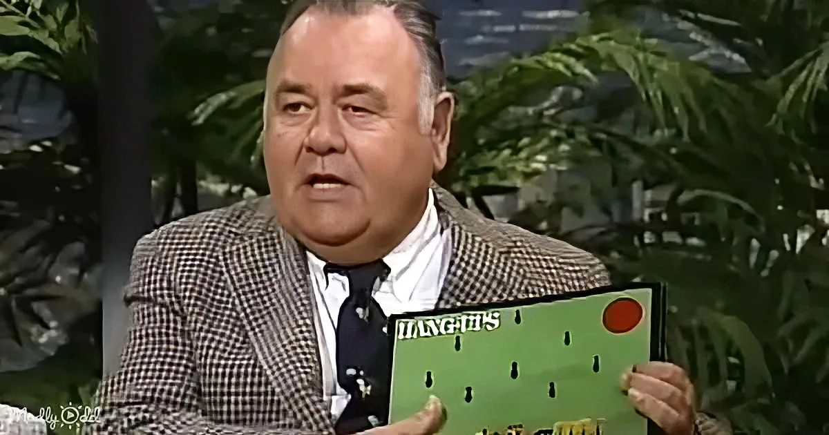 A man in a checkered suit holds a green board game titled "Hang-Ups" with a red sun and black figures.