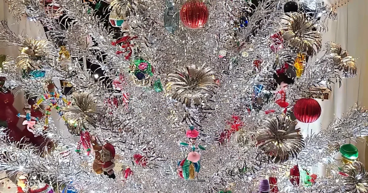 A silver Christmas tree adorned with colorful ornaments, tinsel, and festive decorations.