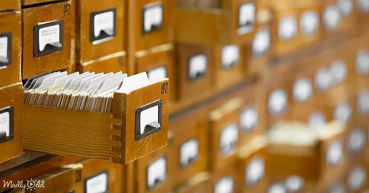 A wooden drawer with cards pulled out, part of a larger filing system.