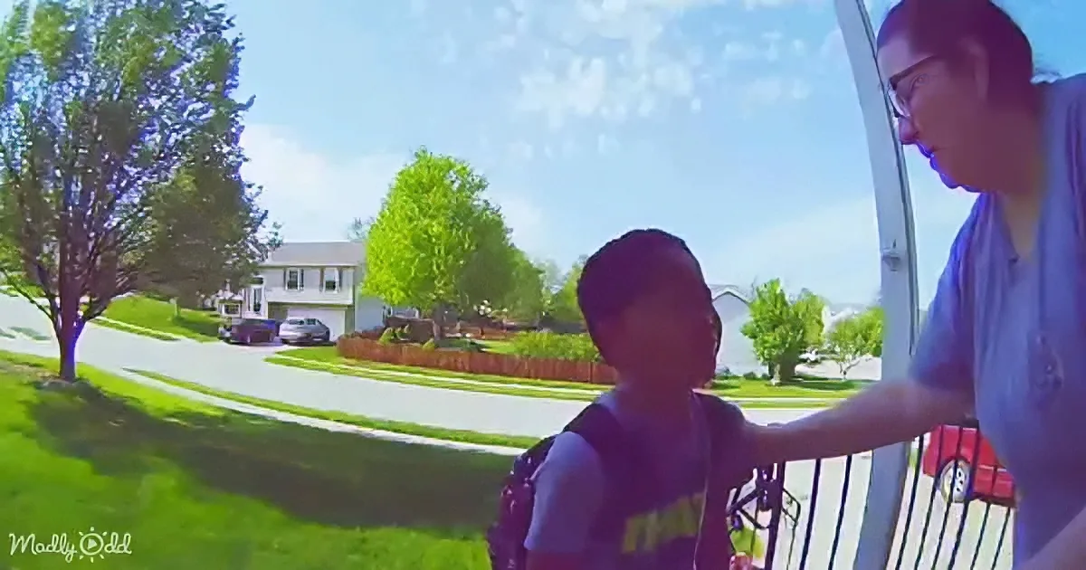 A child in a backpack stands near a woman on a porch, with a suburban neighborhood in the background.