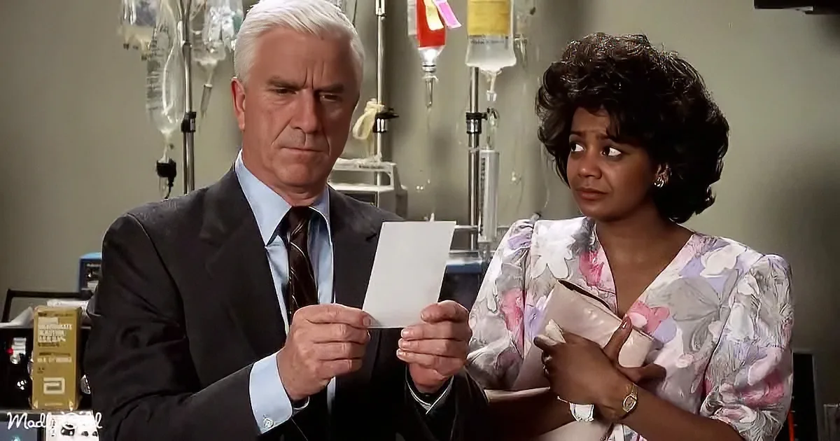 A man in a suit holds a paper, appearing concerned, while a woman in a floral dress looks on, holding a cup.