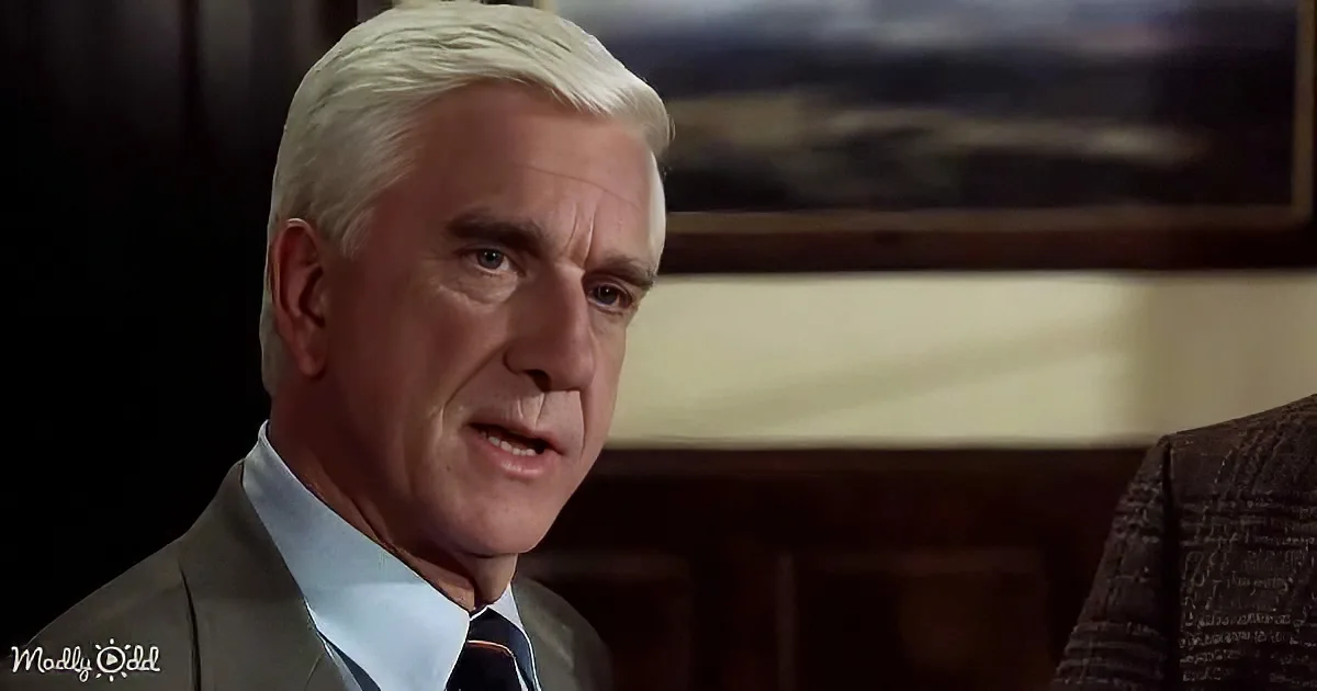 A man with white hair in a suit and tie, looking to the side with a serious expression.