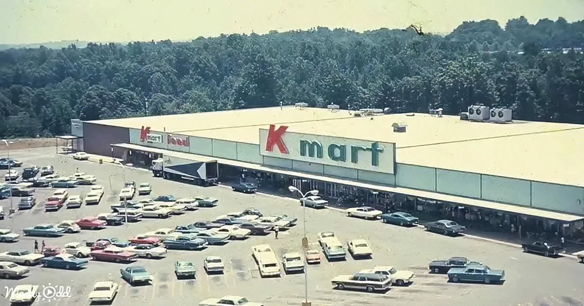 A Kmart store with a large parking lot filled with vintage cars, surrounded by trees.