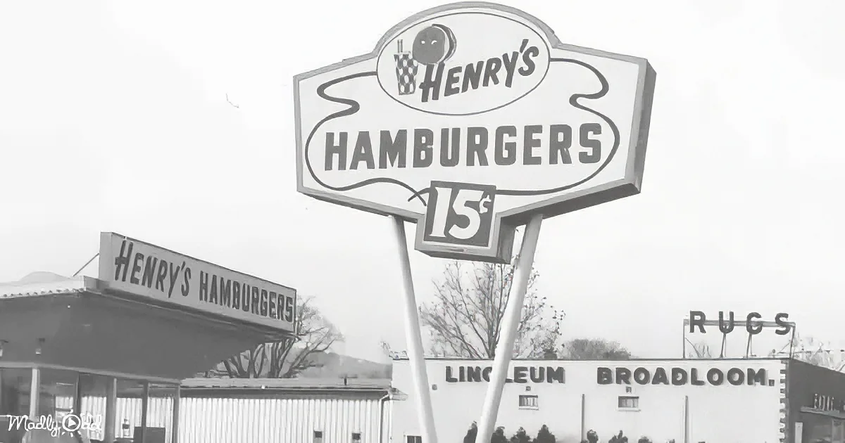 Henry's Hamburgers sign with "15¢" and retro design, black and white, with surrounding businesses.
