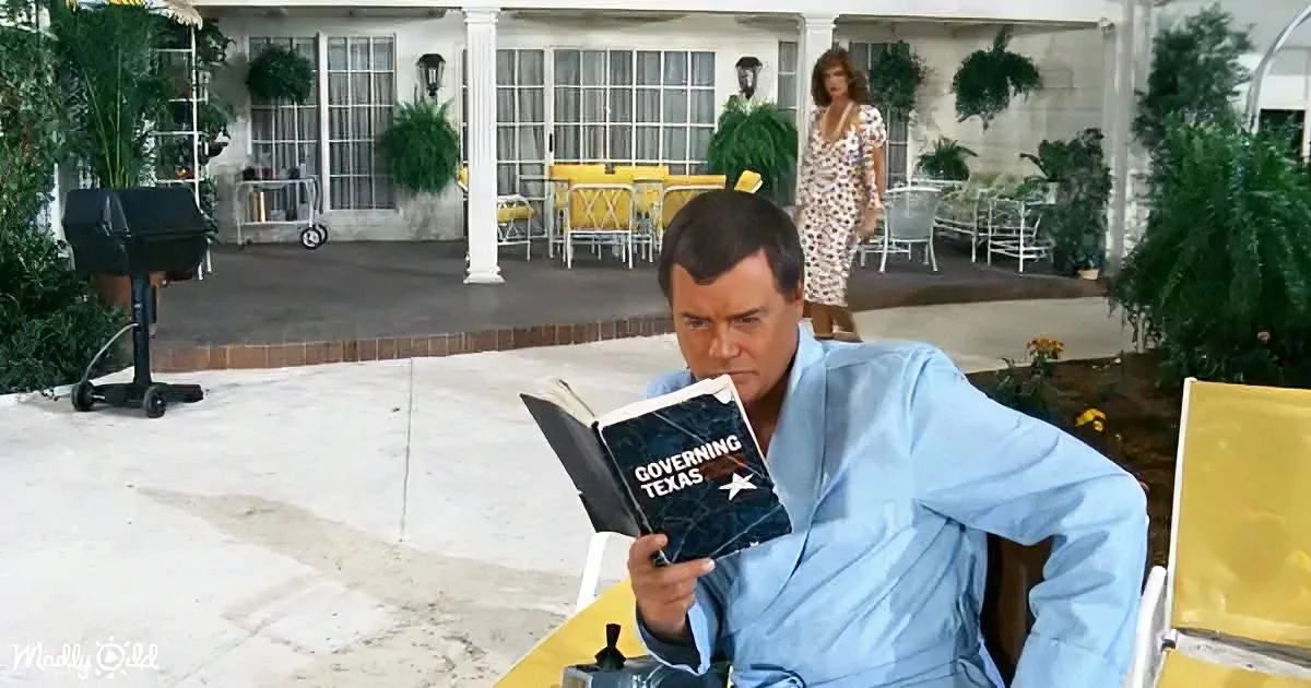 A man in a blue shirt reads "Governing Texas" while sitting on a yellow chair, with a grill and woman in the background.