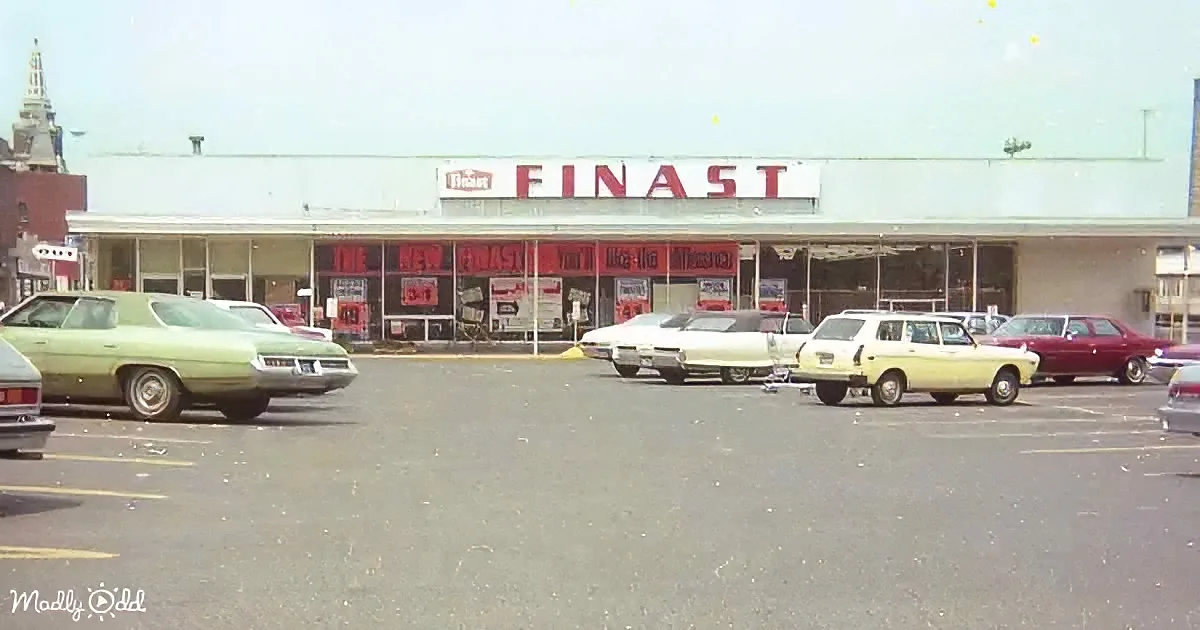 A vintage Finast store with classic cars parked in front, showcasing mid-20th-century automotive design.