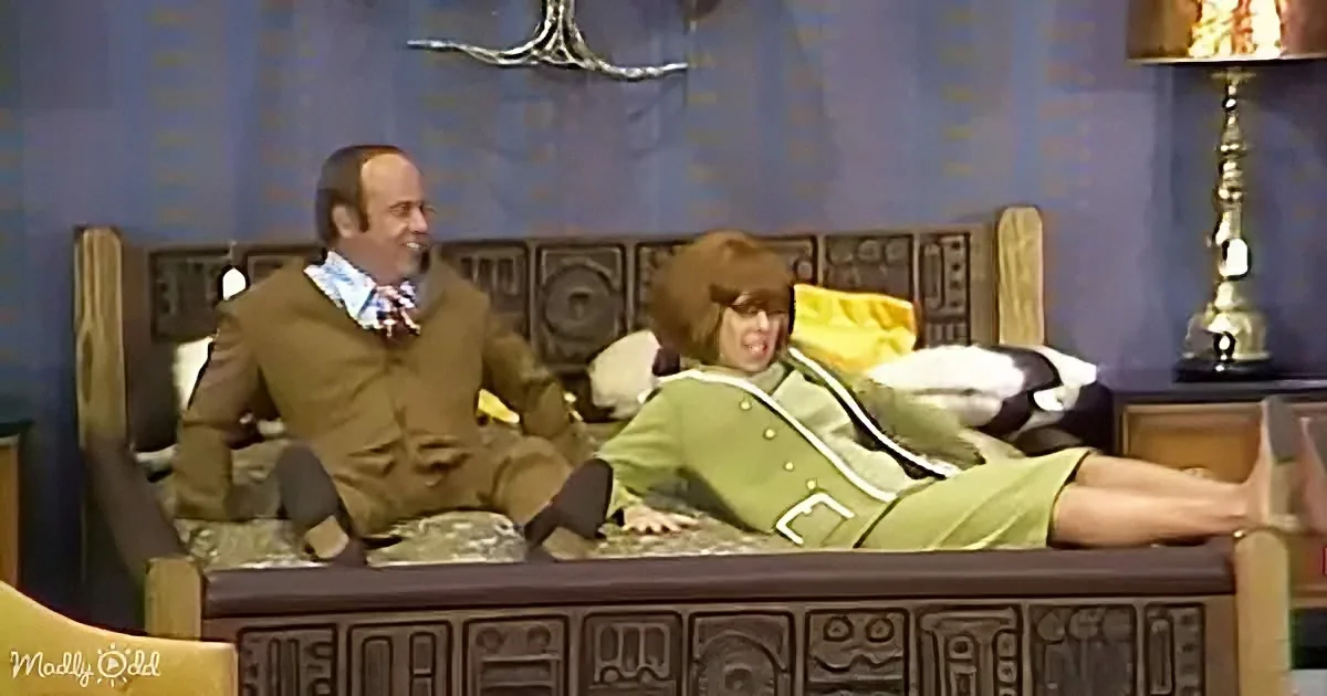 A man in a brown outfit sits on a bed, while another in a green outfit lies down, both appearing relaxed.