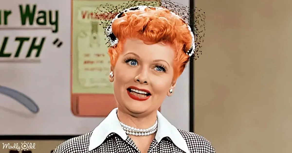 A woman with red hair and pearls smiles in a black-and-white checkered shirt, wearing a black veil.