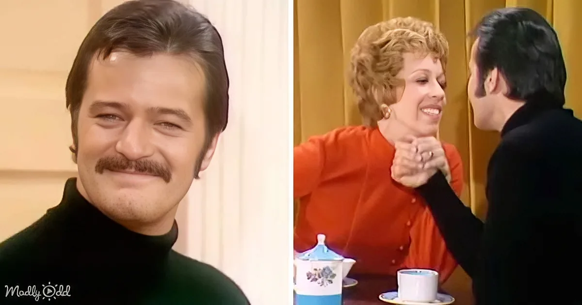 A man with a mustache in a green turtleneck smiles, while a woman in an orange blouse shakes hands with another person in...