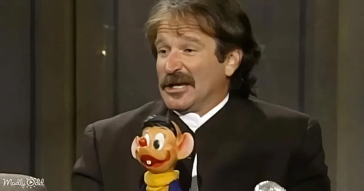 A man in a suit holds a puppet with a surprised expression.