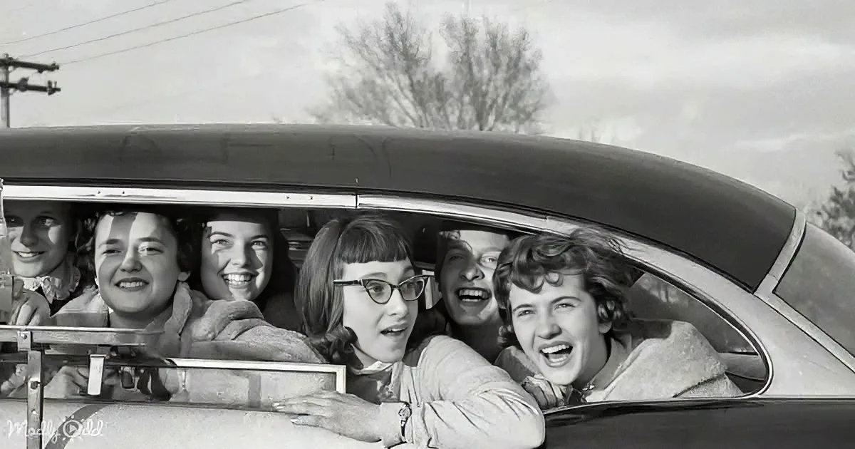 Six smiling people in a vintage car, enjoying a road trip together.